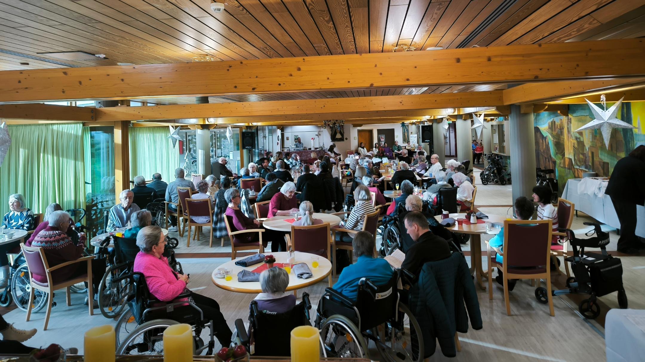 Das Foto zeigt viele Gäste und Bewohner am Heiligmorgen in einem Raum im Seniorenheim St. Klara