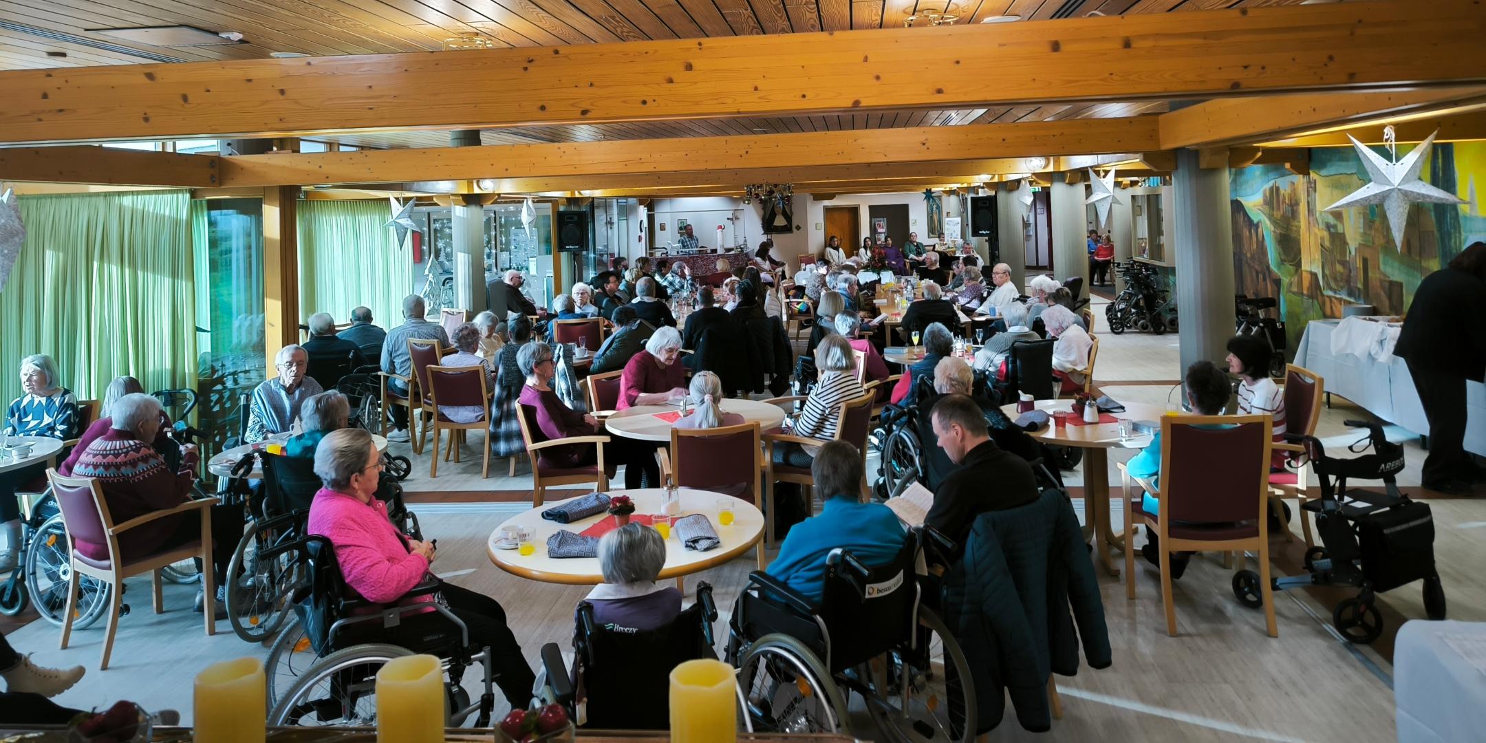 Das Foto zeigt viele Gäste und Bewohner am Heiligmorgen in einem Raum im Seniorenheim St. Klara