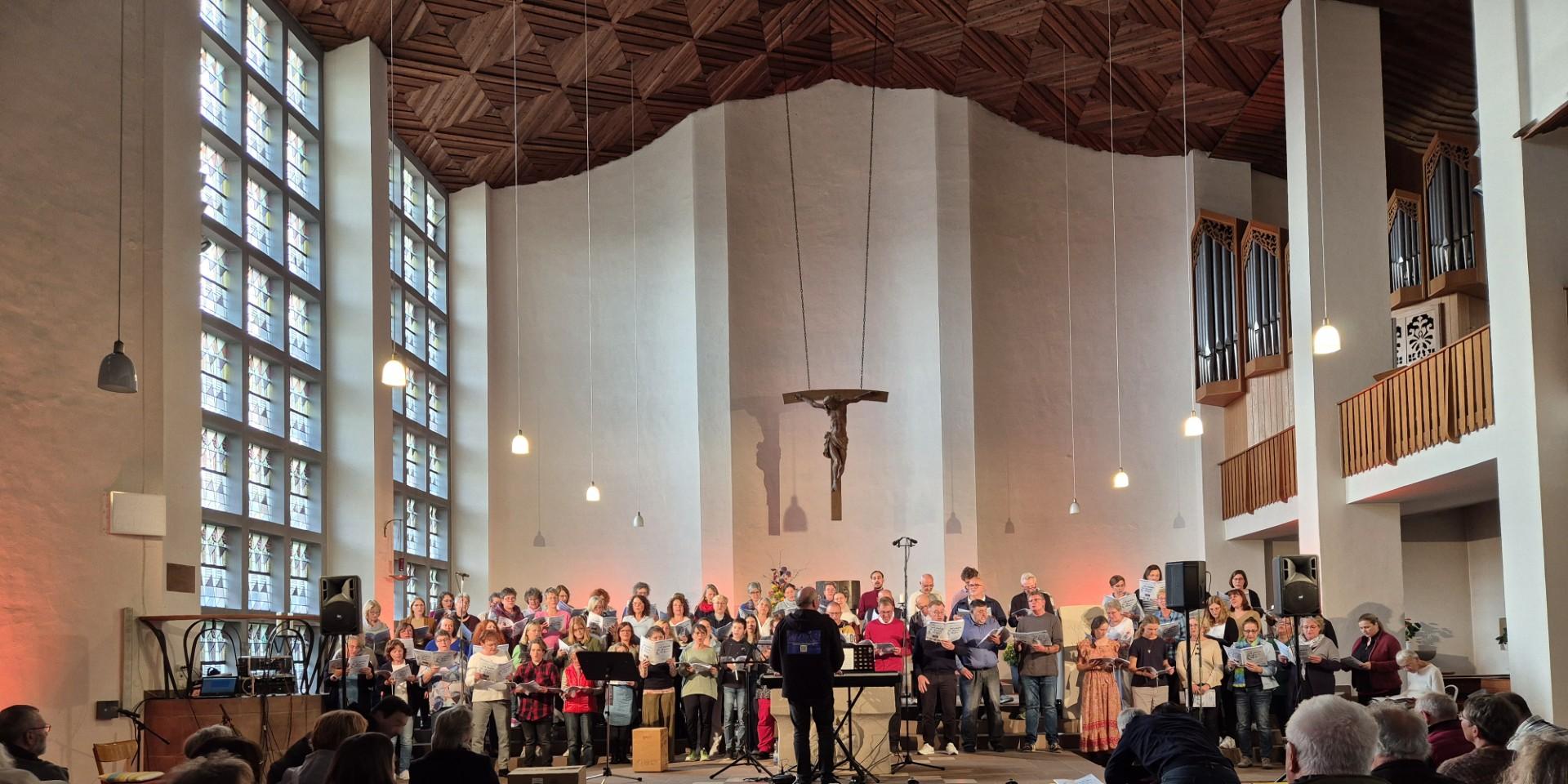 Mehr als 80 Sängerinnen und Sänger singen in einer modern gestalteten Kirche.