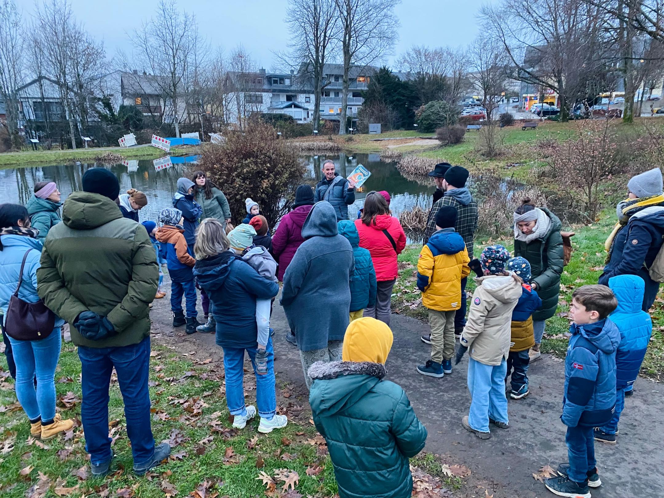 Eine Gruppe von Menschen steht an einem Weiher und hört dem Redner aufmerksam zu. (c) Sandra Cäsar Eine Gruppe von Menschen steht an einem Weiher und hört dem Redner aufmerksam zu.