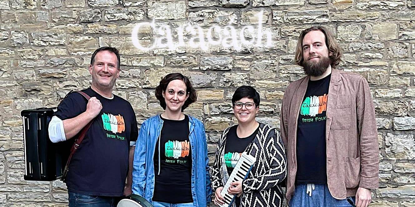 Copilot said:  Vier Personen der Irish-Folk-Band stehen mit Instrumenten vor einer Natursteinmauer mit dem Schriftzug „Caracách“.