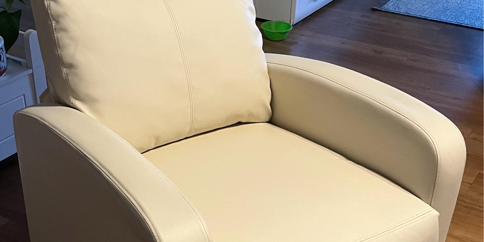 Ein beigefarbener, gepolsterter Relaxsessel mit hoher Rückenlehne und geschwungenen Armlehnen.