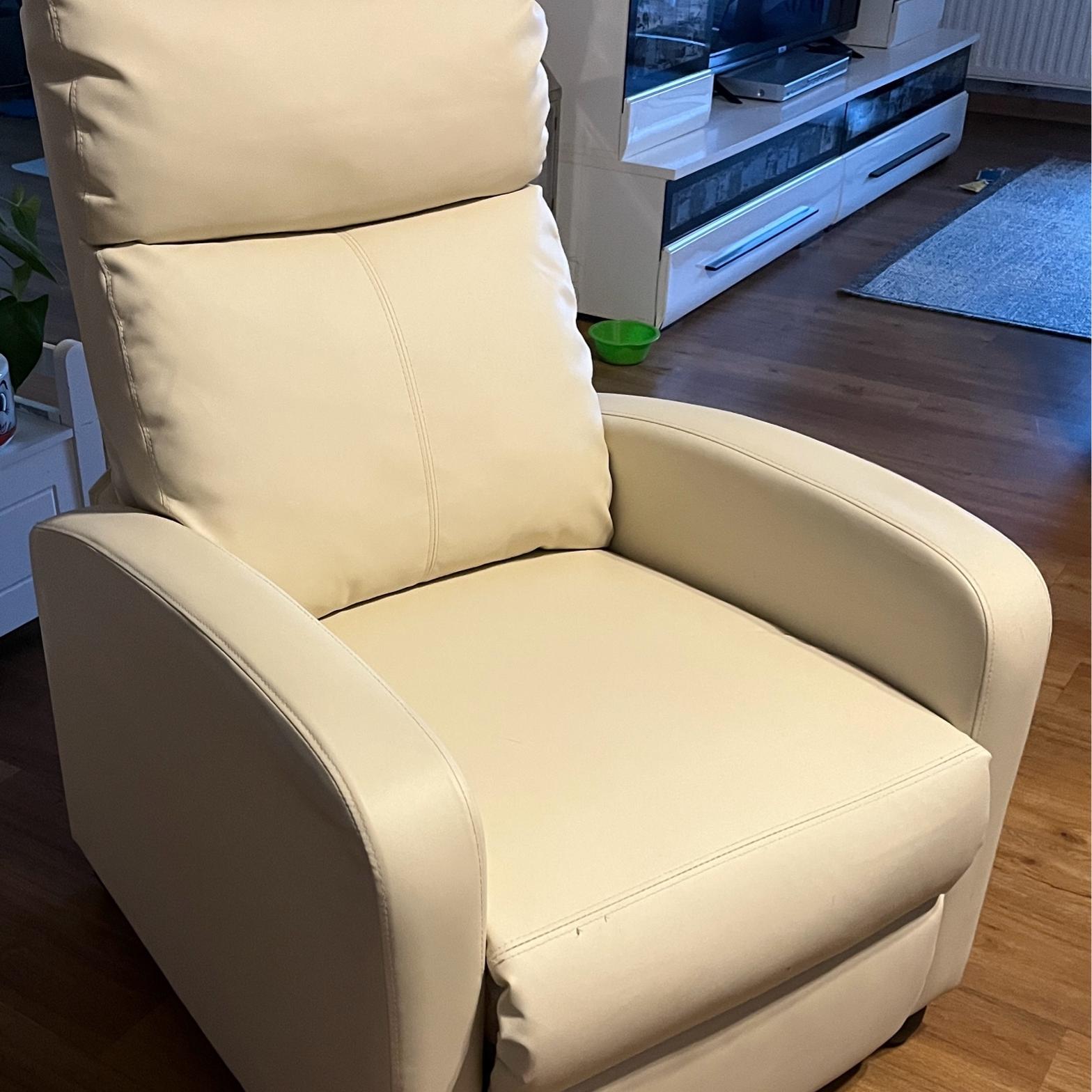 Ein beigefarbener, gepolsterter Relaxsessel mit hoher Rückenlehne und geschwungenen Armlehnen.