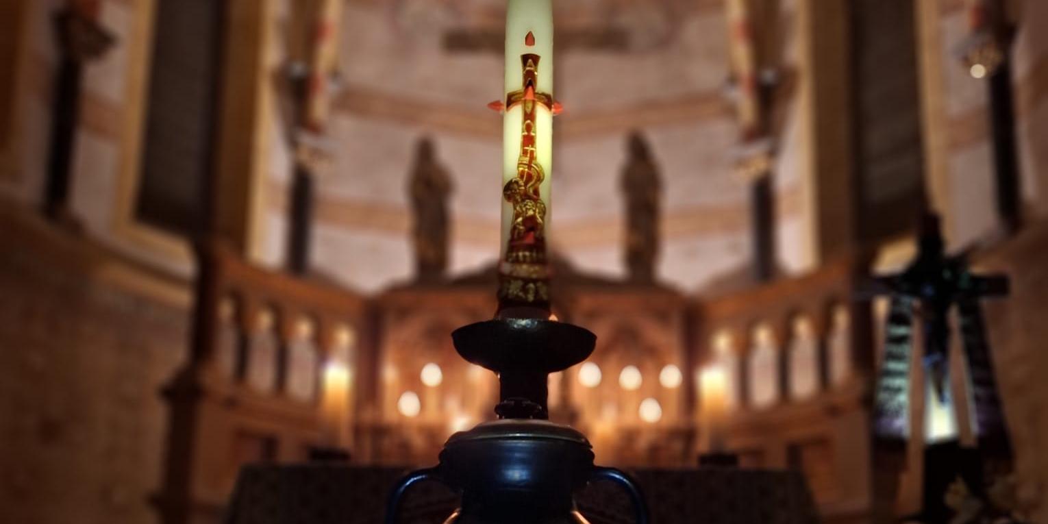 Eine brennende Kerze im Vordergrund, dahinter der festlich beleuchtete Innenraum einer Kirche. (c) Pfarrer Kai Georg Quirin Eine brennende Kerze im Vordergrund, dahinter der festlich beleuchtete Innenraum einer Kirche.