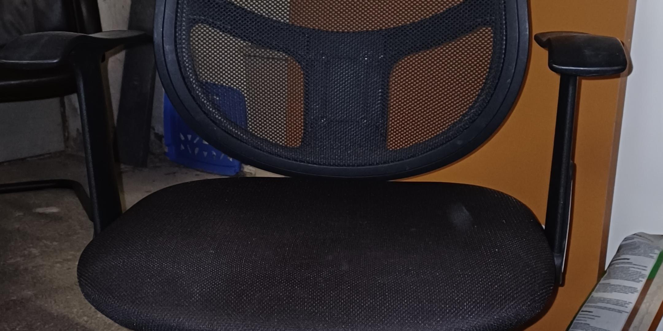 Der Stuhl ist ein schwarzer Bürostuhl mit Netzrücken, gepolsterter Sitzfläche, Kunststoffarmlehnen und einer fünfarmigen Basis mit Rollen.