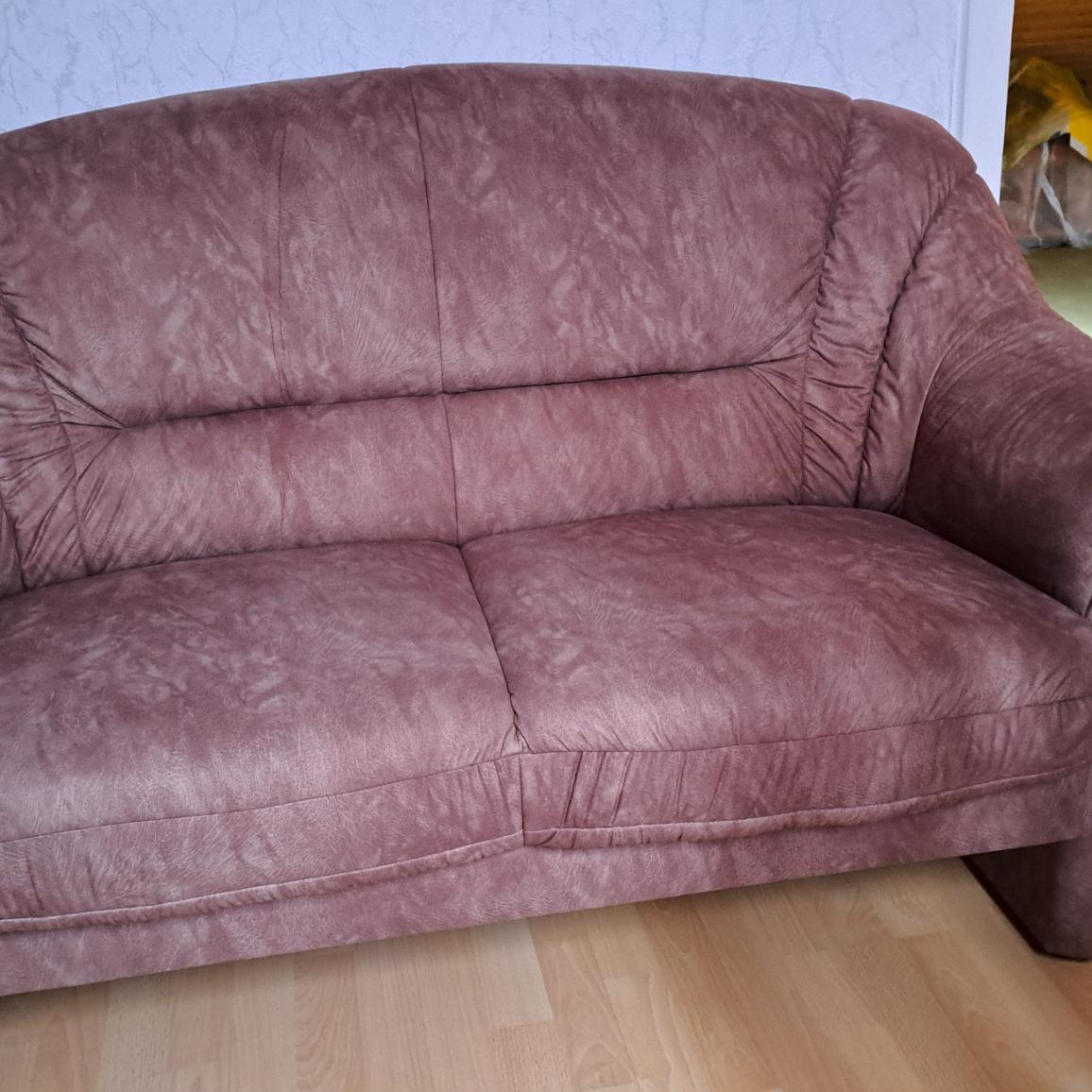 Ein kompakter, brauner Zweisitzer mit gepolsterten Armlehnen und Rückenlehne.