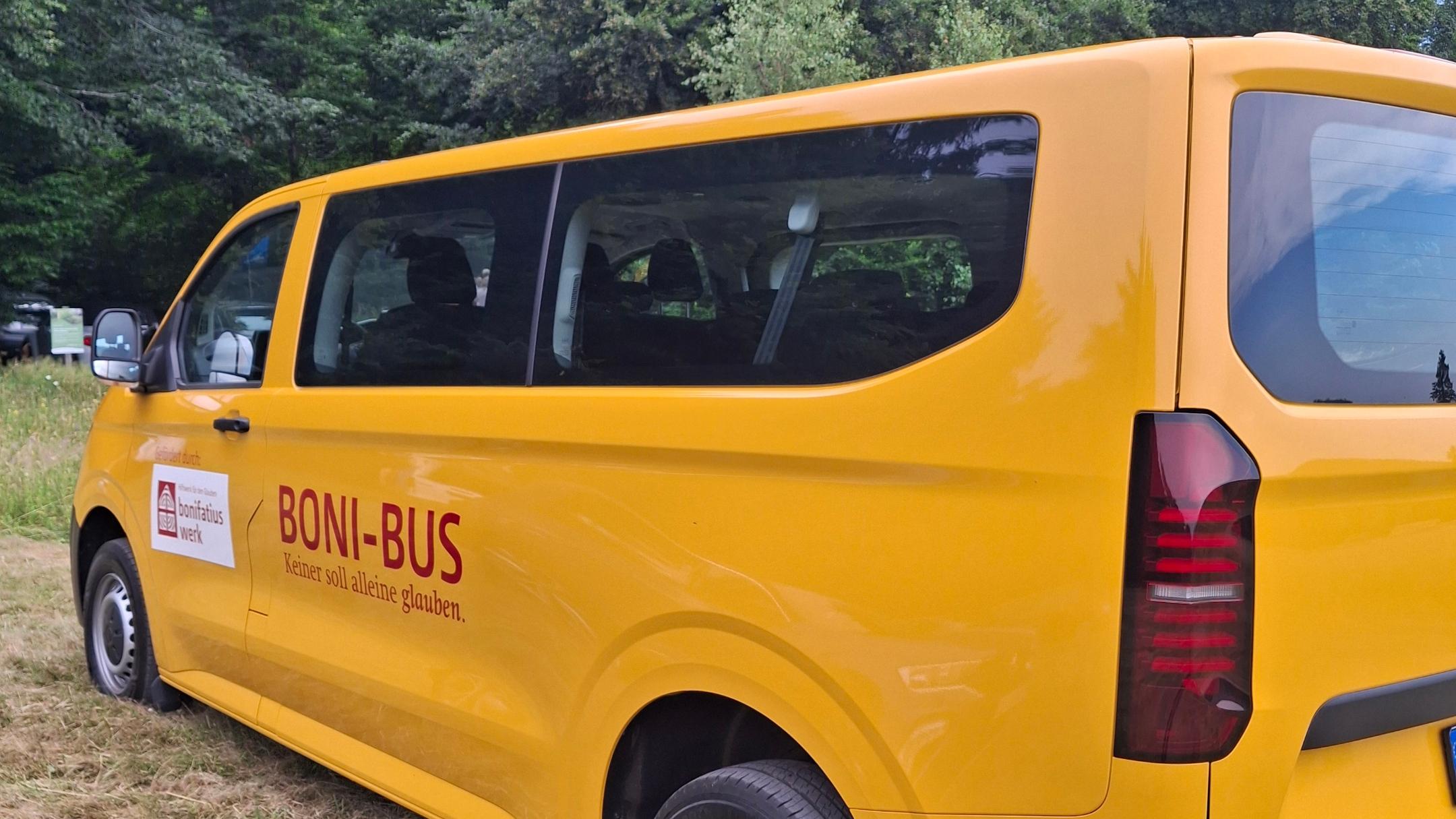 Ein gelber BONI-Bus des Bonifatiuswerks steht auf einer Wiese