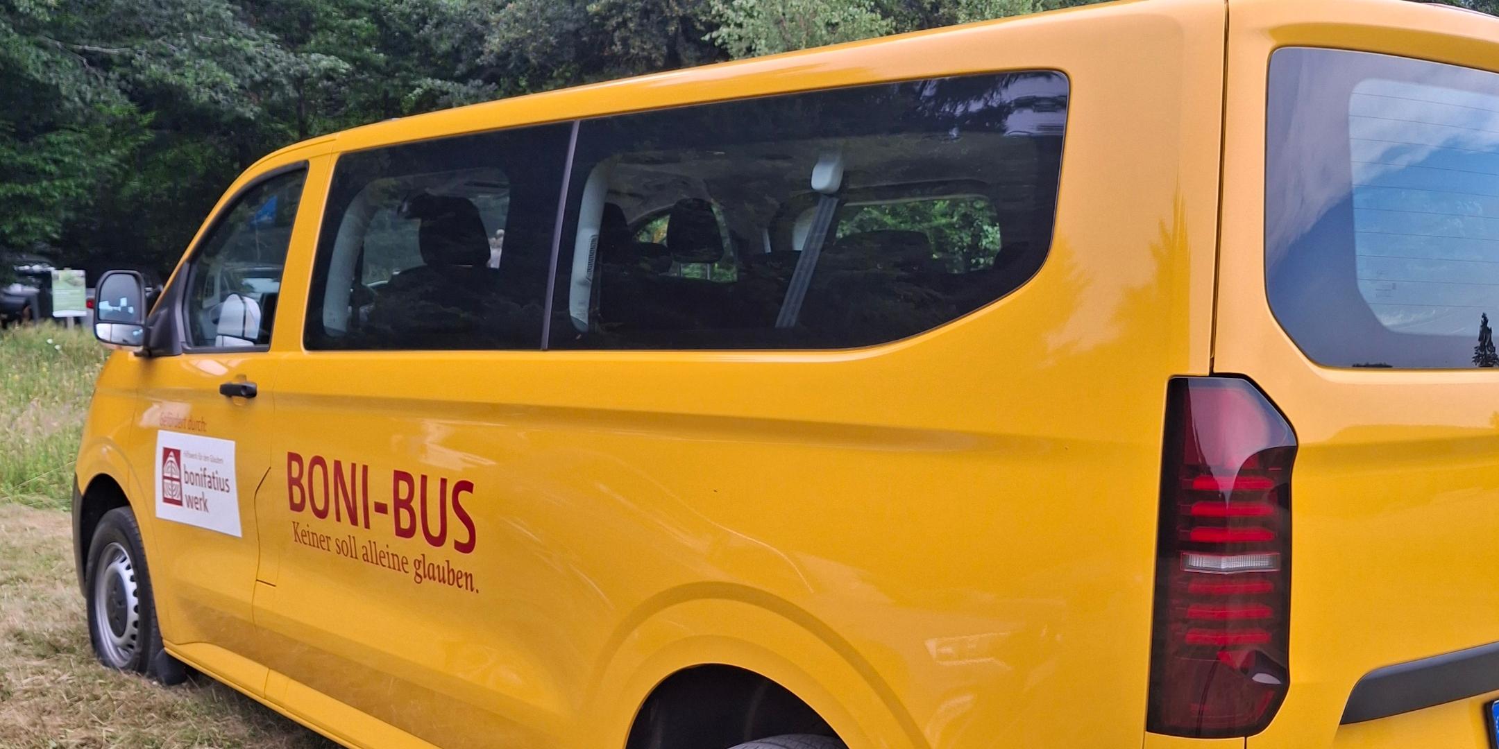 Ein gelber BONI-Bus des Bonifatiuswerks steht auf einer Wiese