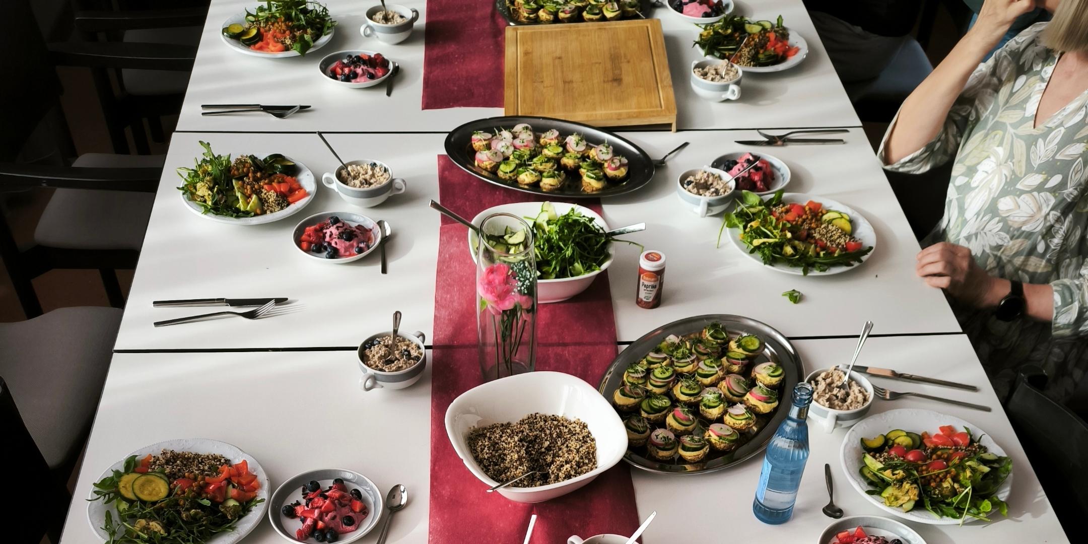 Gemeinsames Essen an einem liebevoll gedeckten Tisch mit vielfältigen, antientzündlichen Gerichten wie frischen Salaten, Gemüse, Beeren-Desserts und gesunden Snacks.