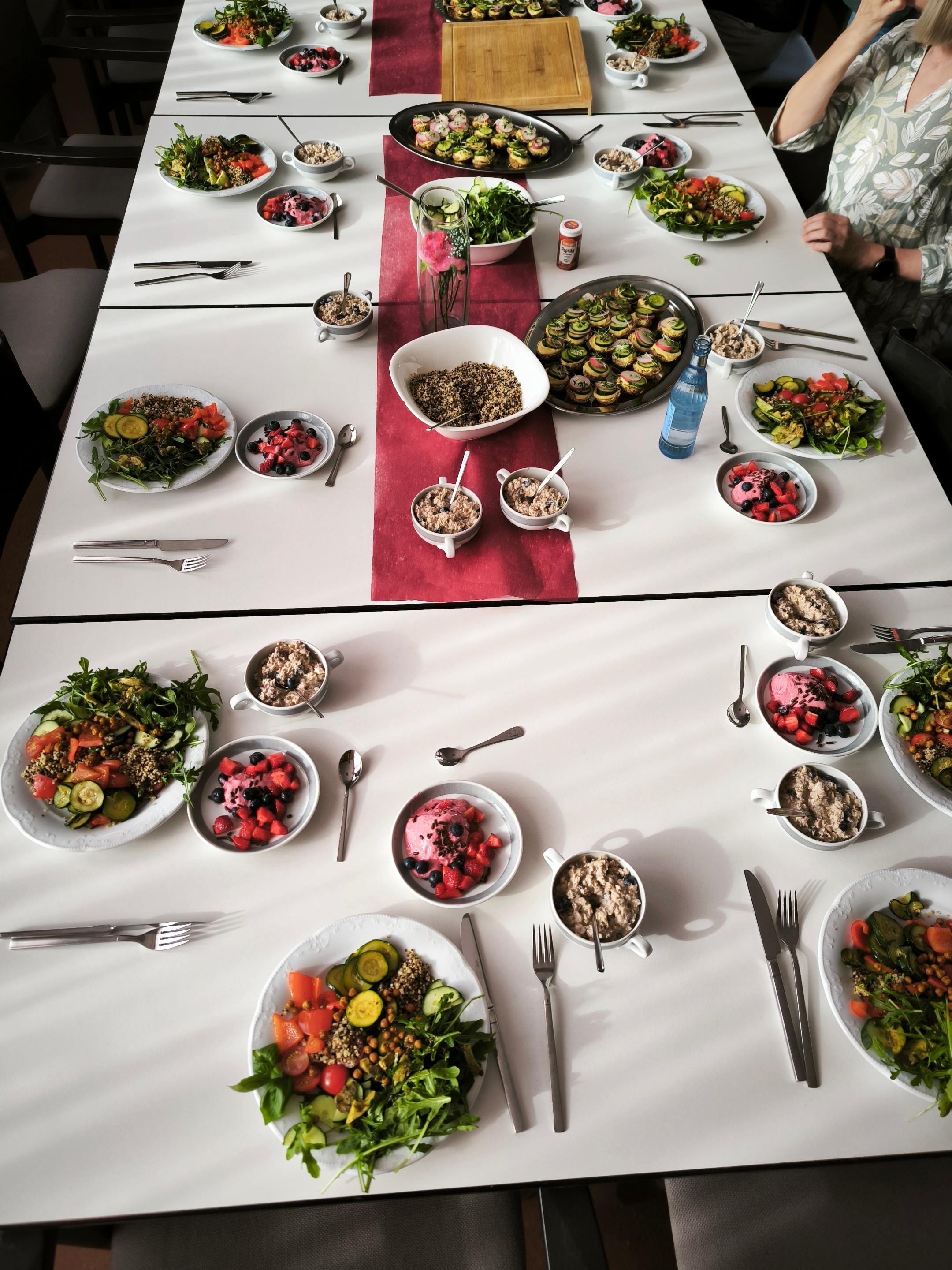 Gemeinsames Essen an einem liebevoll gedeckten Tisch mit vielfältigen, antientzündlichen Gerichten wie frischen Salaten, Gemüse, Beeren-Desserts und gesunden Snacks.