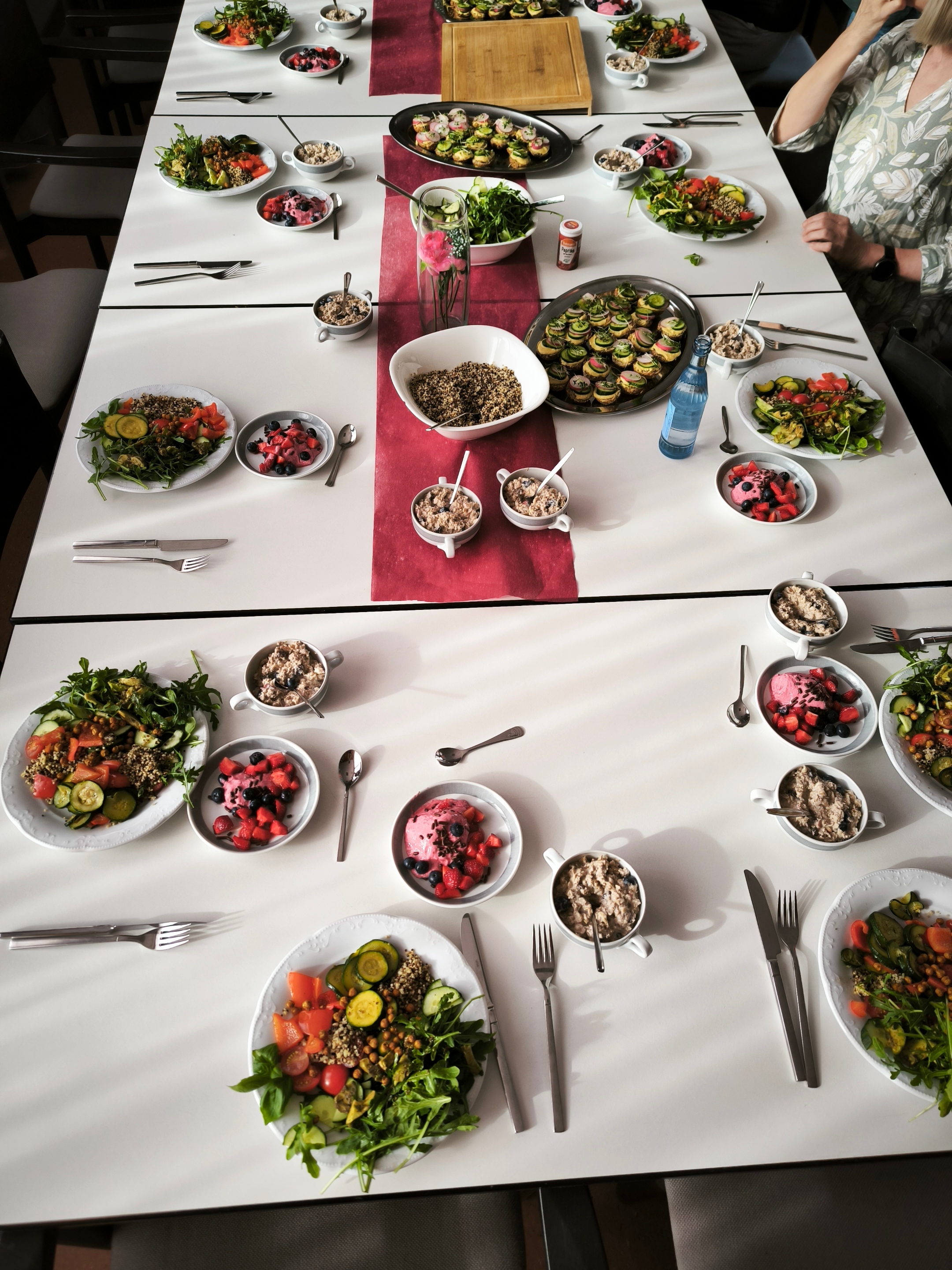 Gemeinsames Essen an einem liebevoll gedeckten Tisch mit vielfältigen, antientzündlichen Gerichten wie frischen Salaten, Gemüse, Beeren-Desserts und gesunden Snacks.
