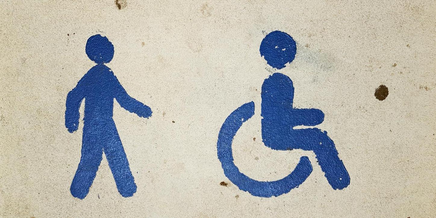 Blaue Symbole für Fußgänger und Rollstuhlfahrer auf beigem Hintergrund.