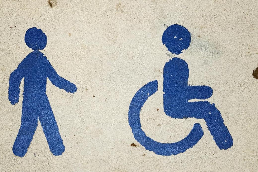 Blaue Symbole für Fußgänger und Rollstuhlfahrer auf beigem Hintergrund.