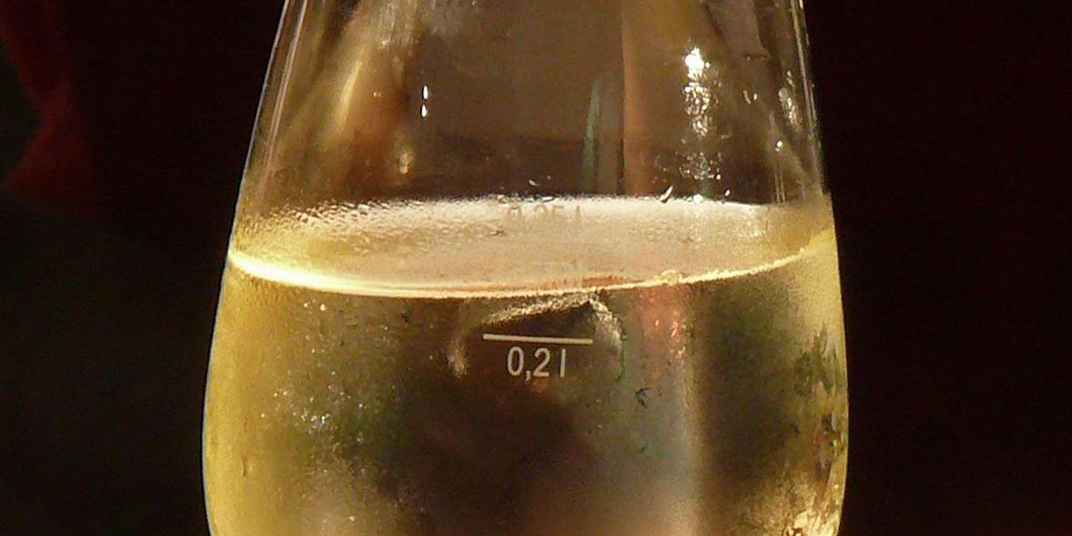 Gefülltes Weißweinglas mit Kondenswassertropfen am Glasrand