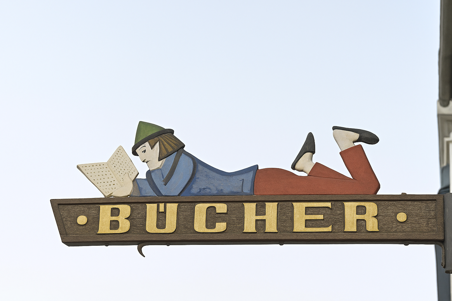 Bücherschild mit einer Figur, die ein Buch liest.