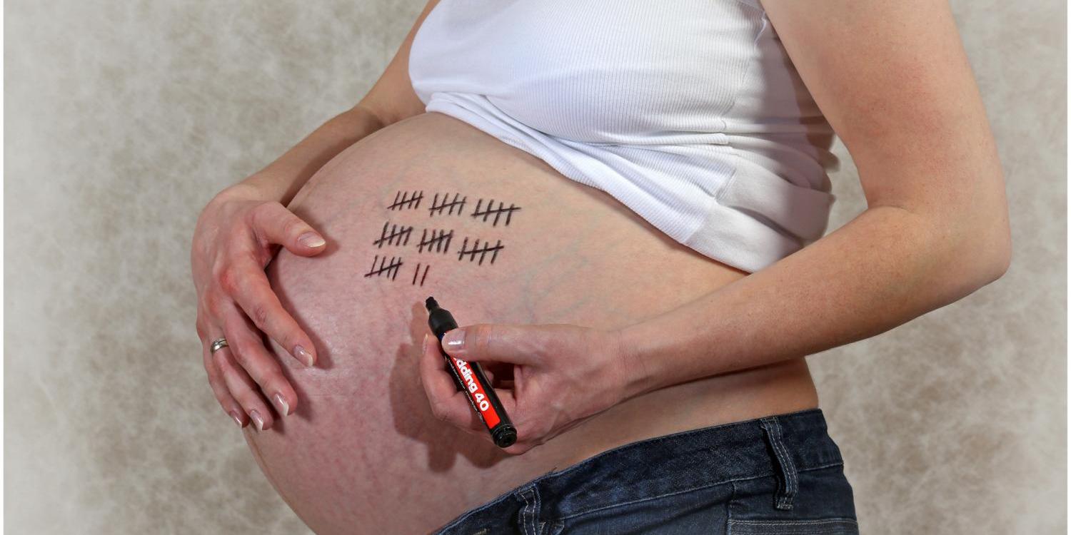 Eine schwangere Frau, die Strichlisten auf ihren Bauch malt – vermutlich zur humorvollen Darstellung der verbleibenden Wochen bis zur Geburt.