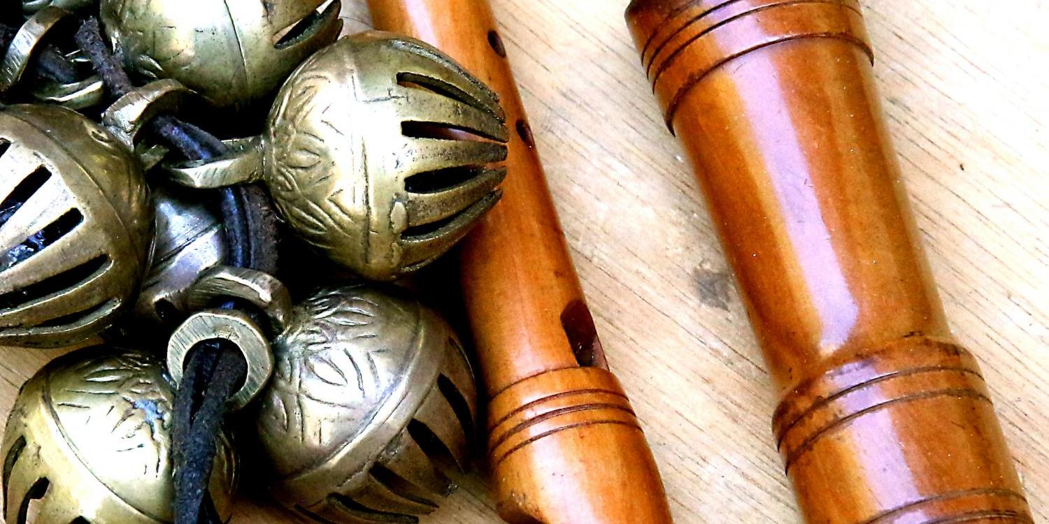 Holzflöten und Metallschellen auf hellem Holztisch
