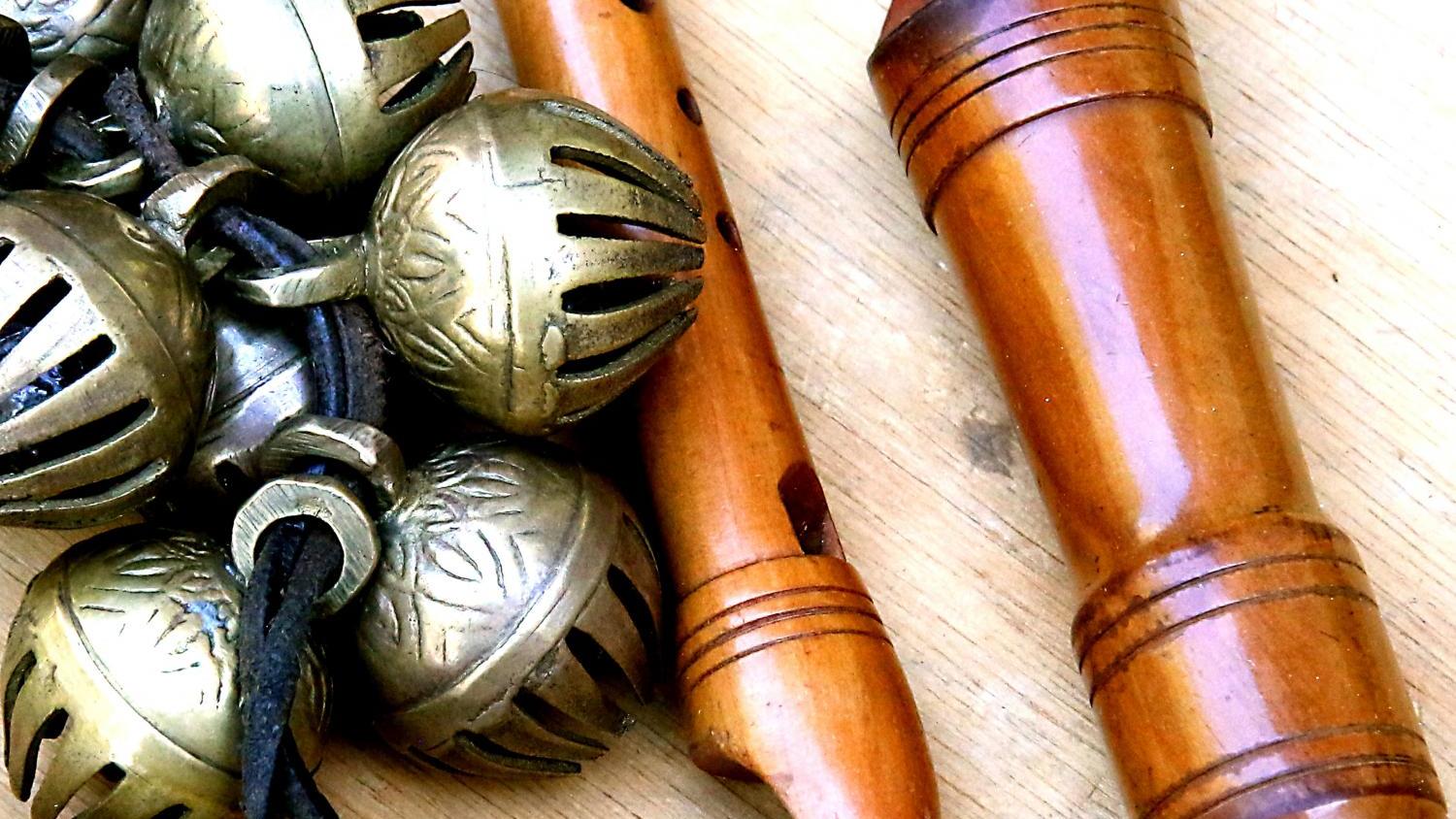 Holzflöten und Metallschellen auf hellem Holztisch