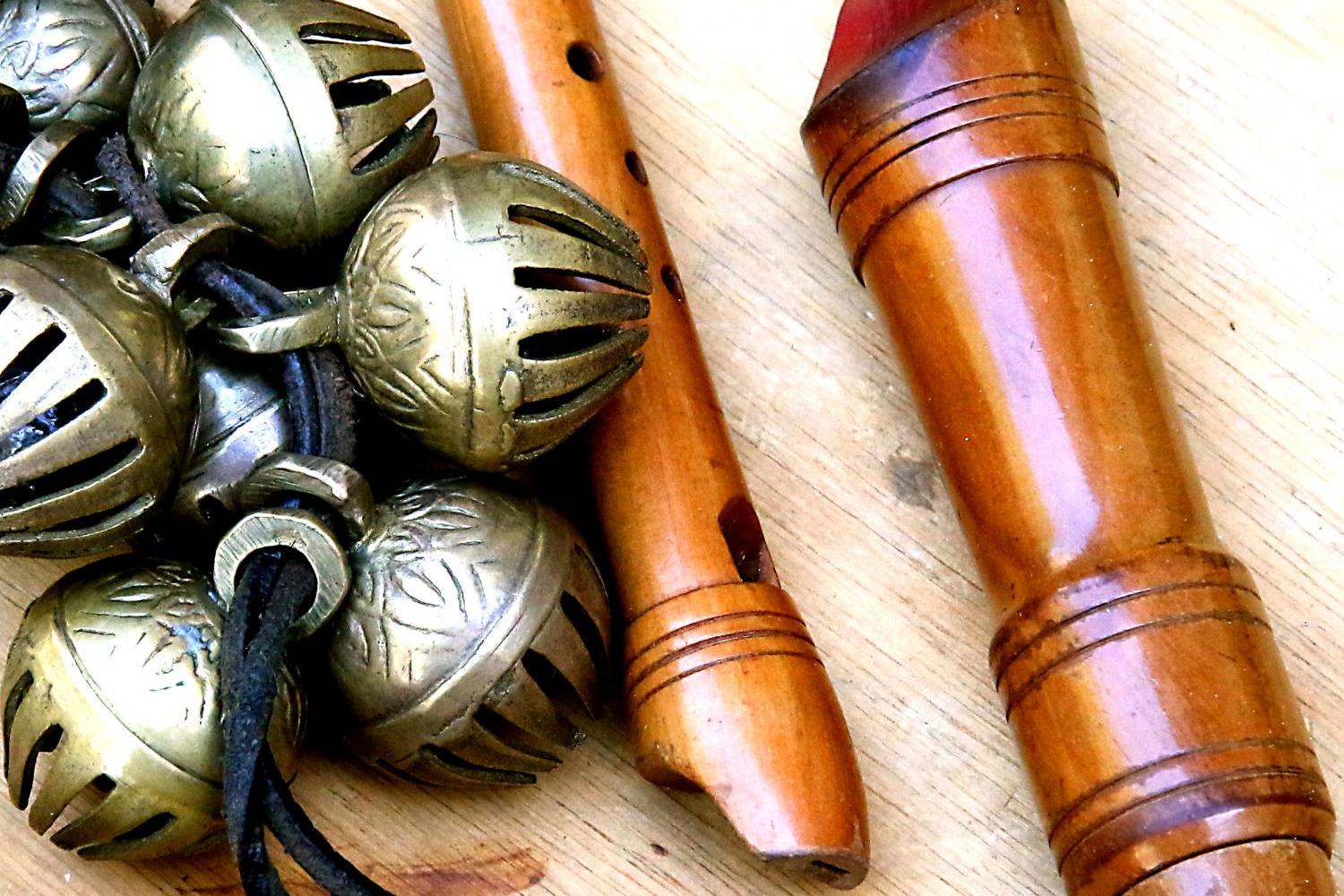Holzflöten und Metallschellen auf hellem Holztisch