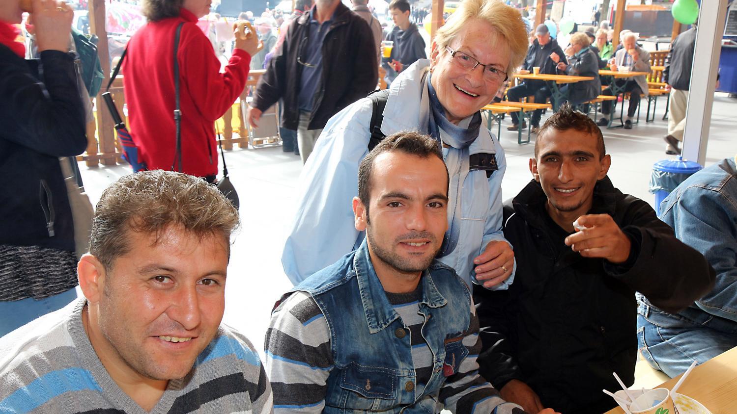 Eine kleine Gruppe von Menschen sitzt und steht gemütlich an Tischen bei einer Essens‑ oder Gemeinschaftsveranstaltung.