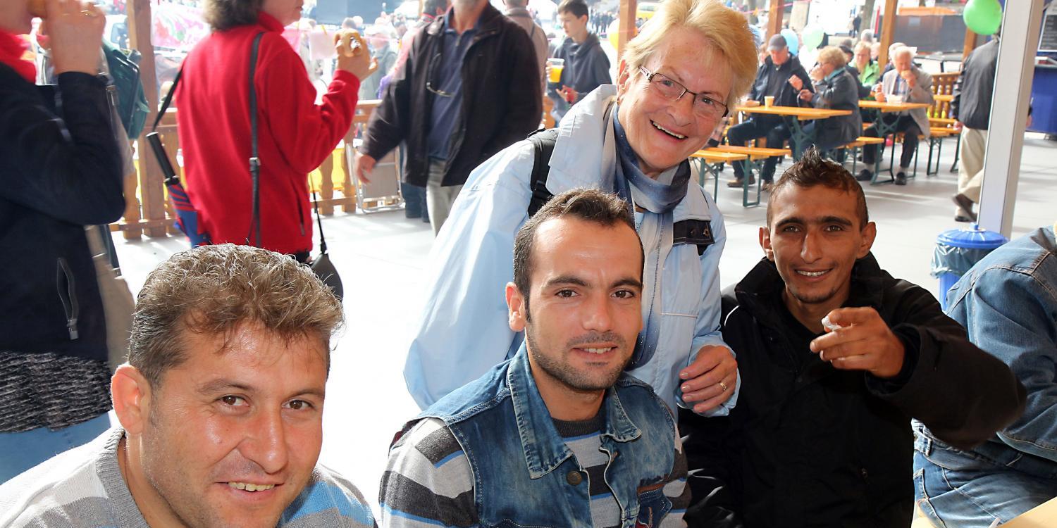 Eine kleine Gruppe von Menschen sitzt und steht gemütlich an Tischen bei einer Essens‑ oder Gemeinschaftsveranstaltung.