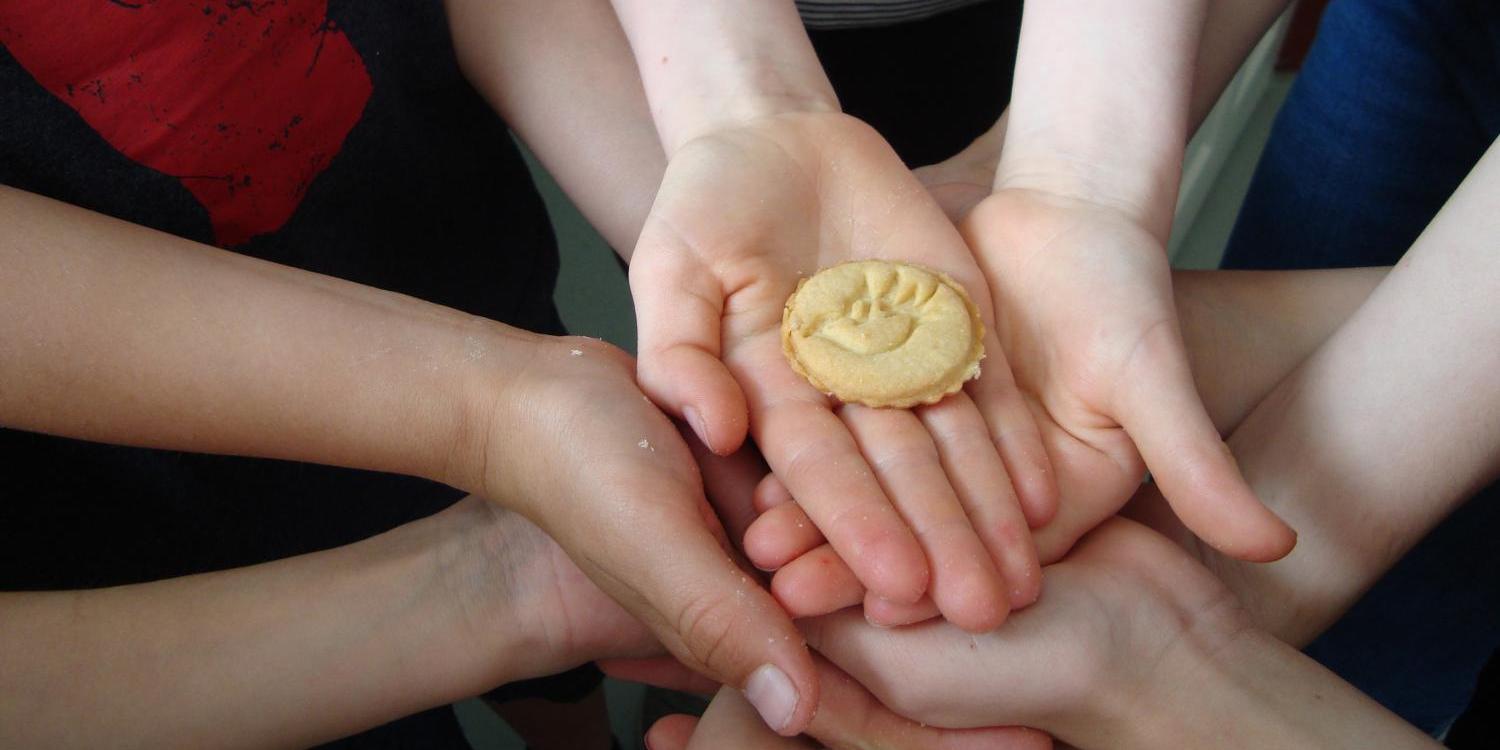 Mehrere Kinderhände halten gemeinsam einen Keks mit dem Symbol einer Pfingsttauben (c) Bild: Ursula Graber In: Pfarrbriefservice.de Mehrere Kinderhände halten gemeinsam einen Keks mit dem Symbol einer Pfingsttauben