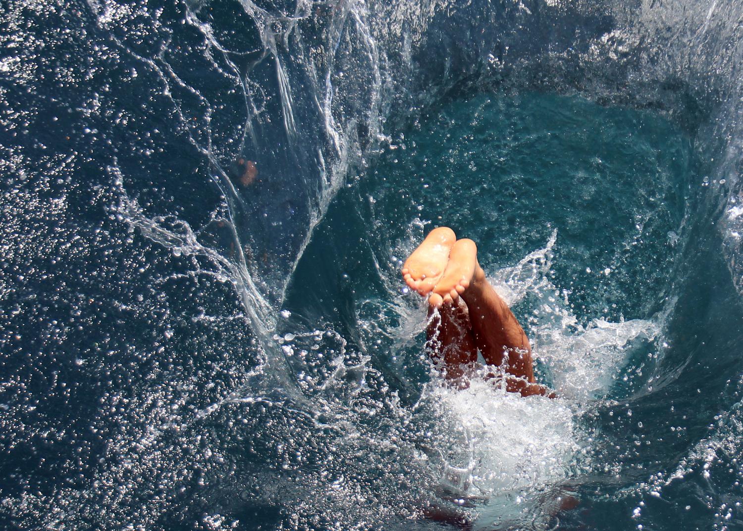 Ein Mensch taucht kopfüber ins Wasser ein und erzeugt dabei einen großen Spritzer