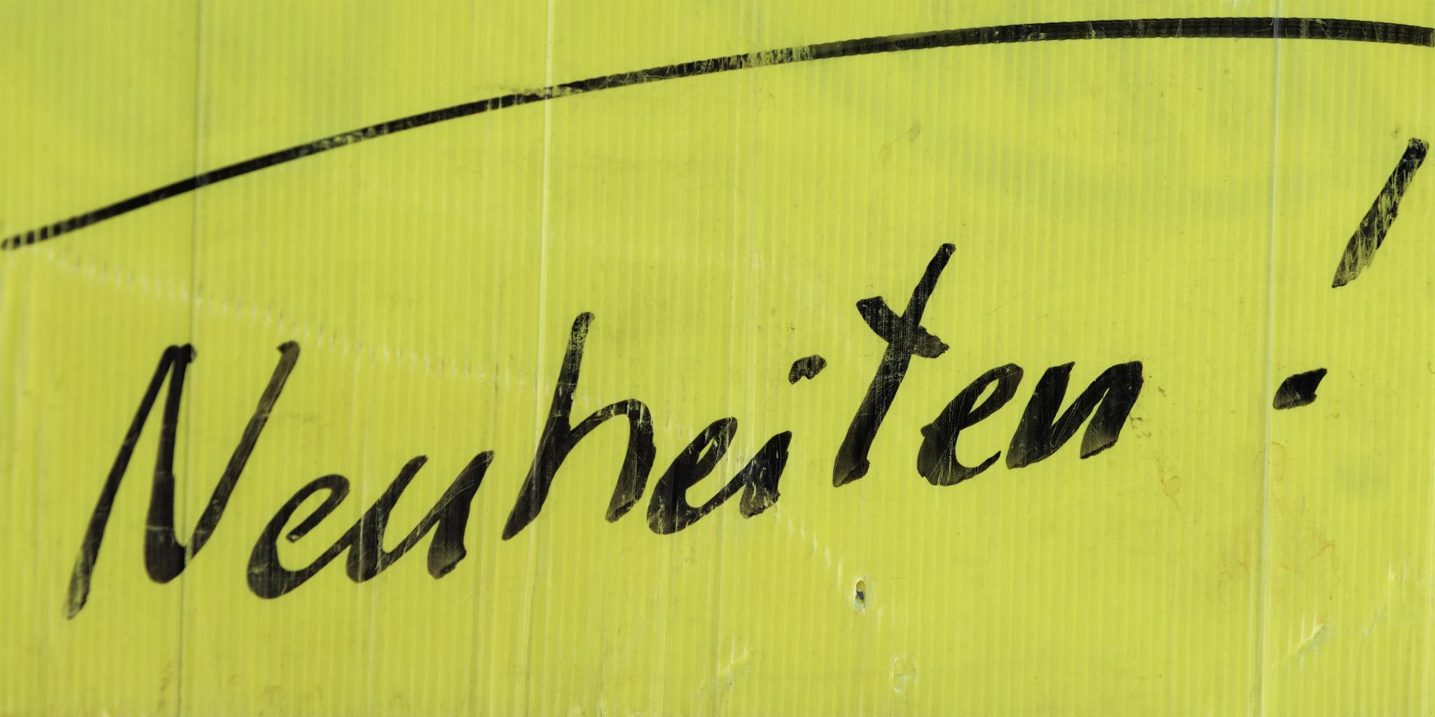 Auf einem neongelben Schild steht in schwarzer Schrift Neuheiten