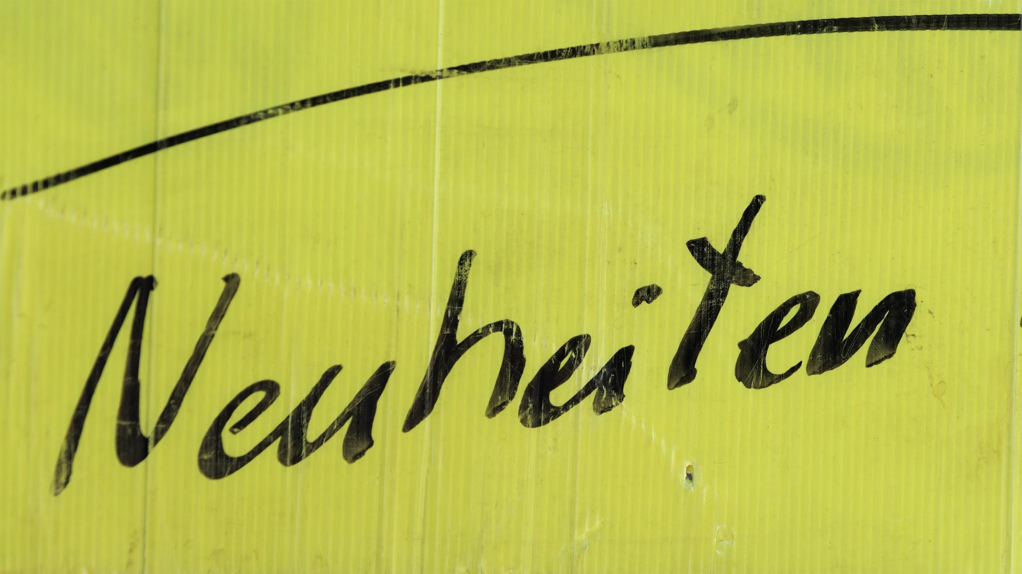 Auf einem neongelben Schild steht in schwarzer Schrift Neuheiten