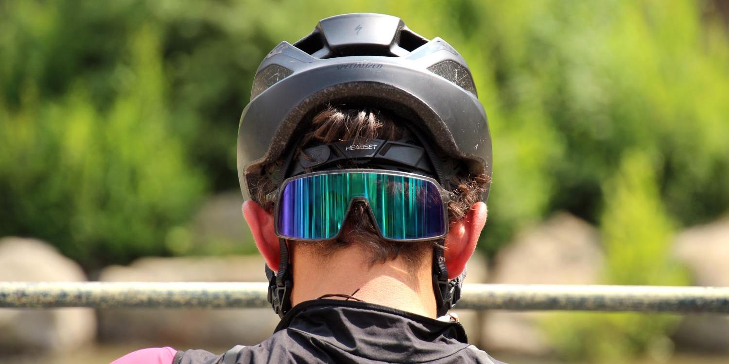 Radfahrer von hinten mit Helm und reflektierender Sportbrille.