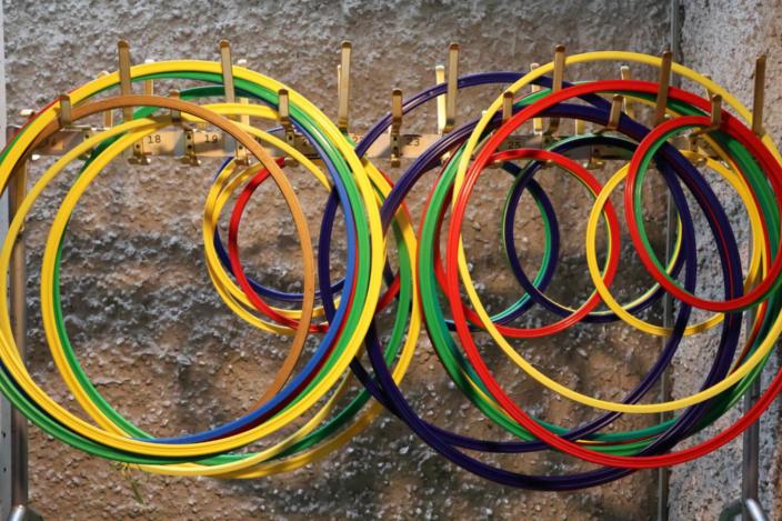 Mehrere bunte Gymnastikreifen hängen ordentlich sortiert an einer Wandhalterung.