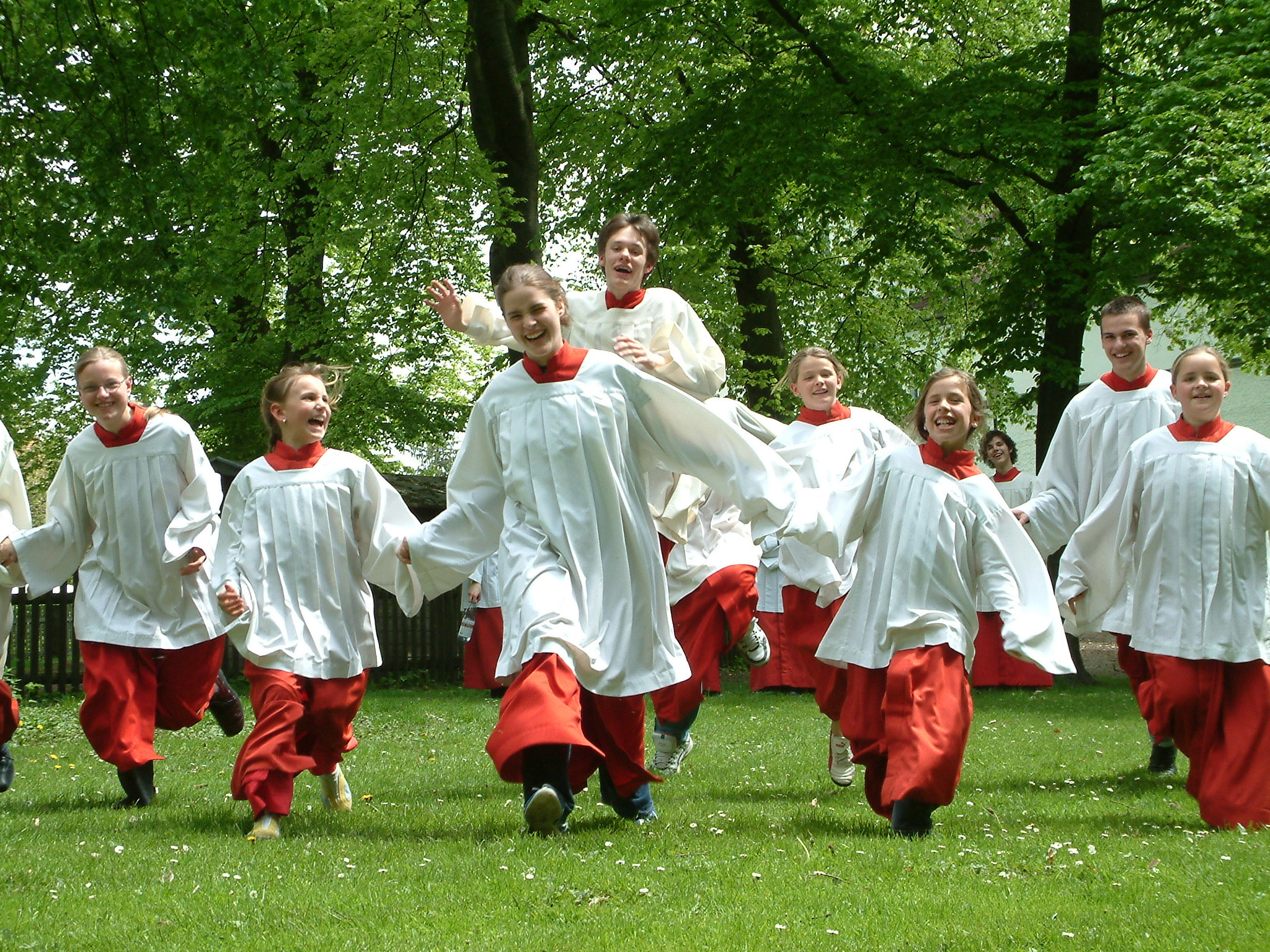 Eine Gruppe von Messdienern läuft fröhlich über eine grüne Wiese.