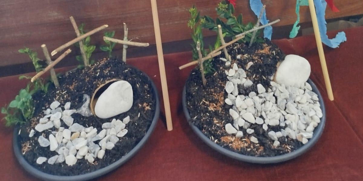 Zwei kleine Oster‑ bzw. Grabgärten mit Palmzweigen, bunt geschmückt mit farbigen Bändern.