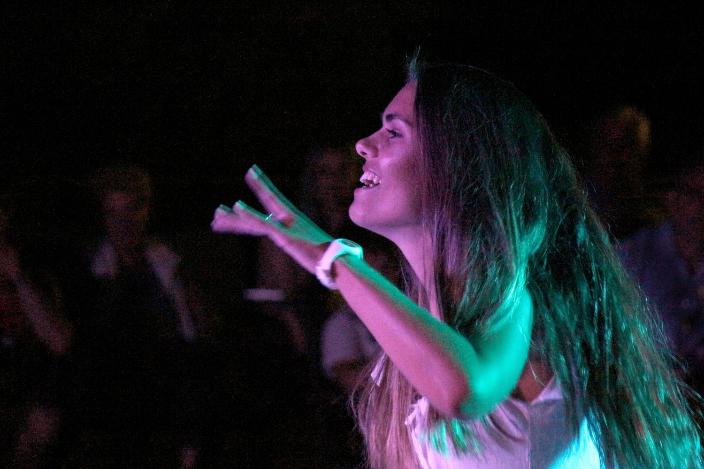 Eine Person tanzt energiegeladen unter farbigem Bühnenlicht.