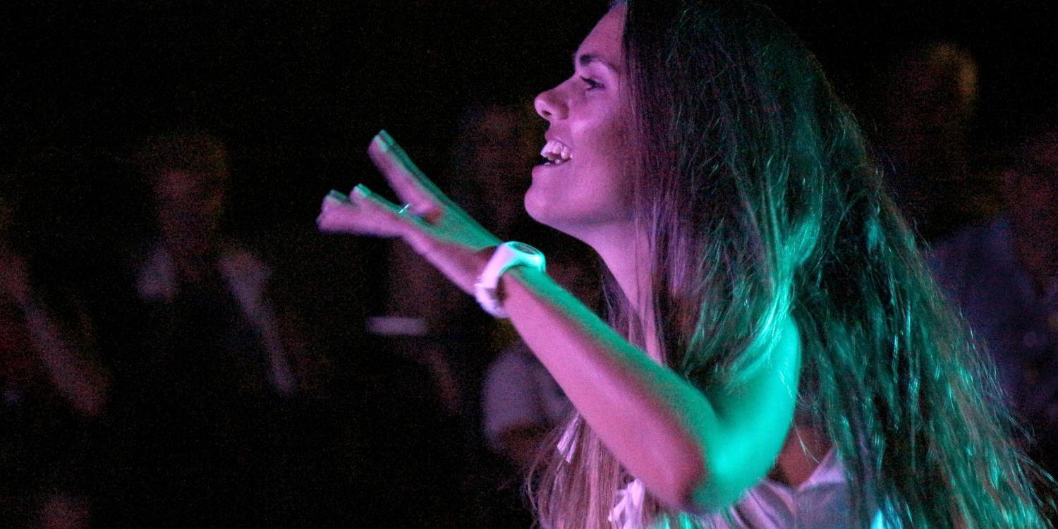 Eine Person tanzt energiegeladen unter farbigem Bühnenlicht.