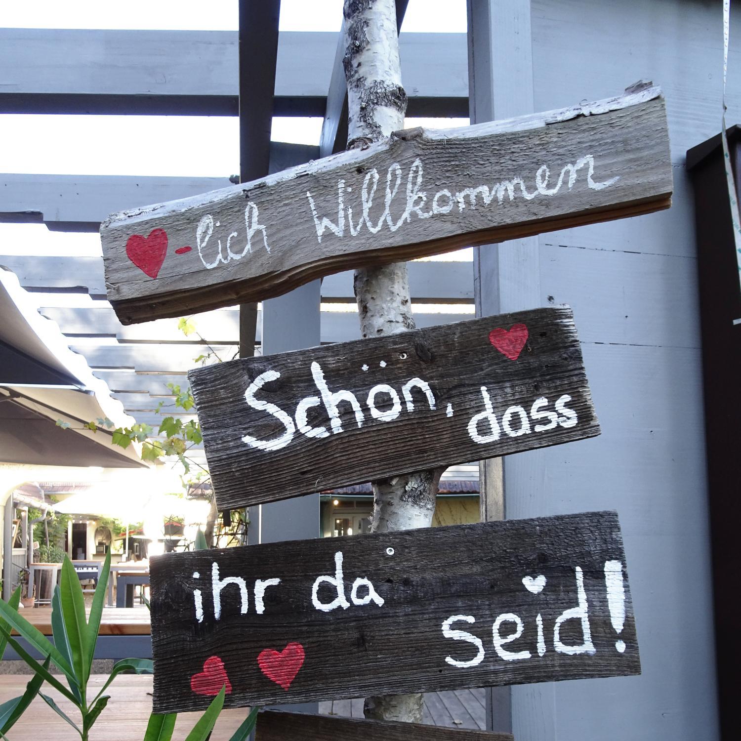 Rustikale Holzschilder mit einem Willkommensgruß und Herzen.