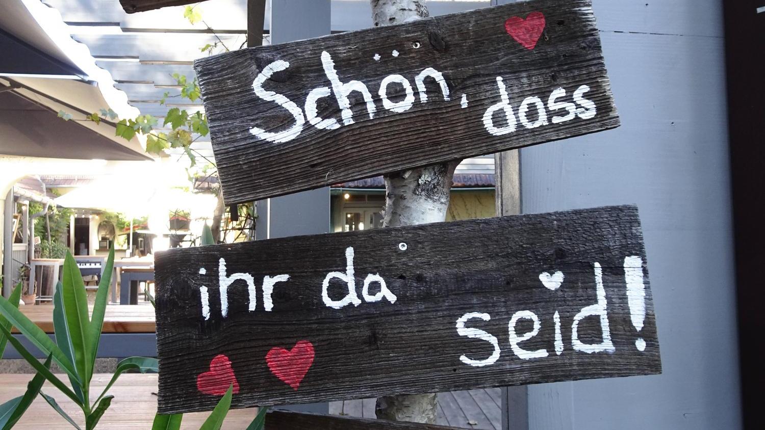 Rustikale Holzschilder mit einem Willkommensgruß und Herzen.