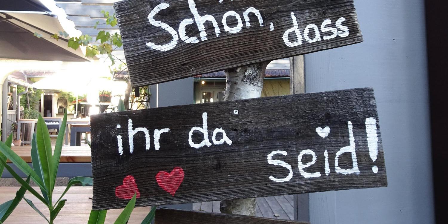 Rustikale Holzschilder mit einem Willkommensgruß und Herzen.