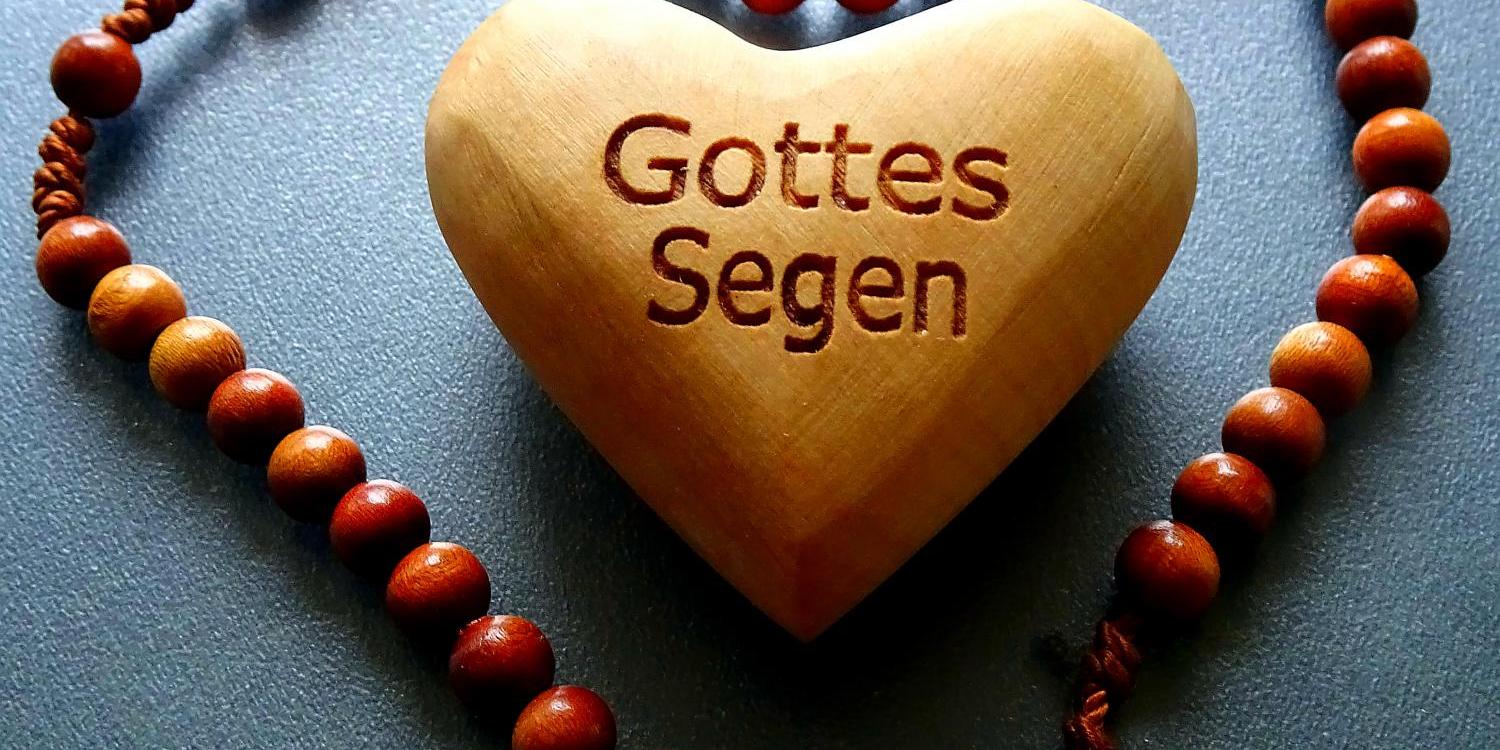 Holzherz mit der Gravur 'Gottes Segen' in einer Perlenkette geformt als Herz.