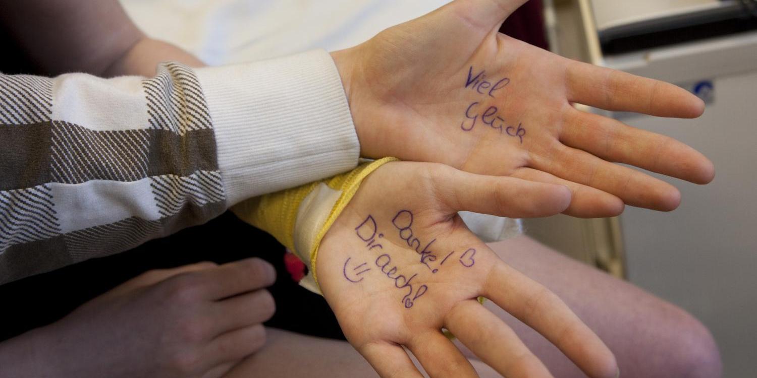 Zwei Hände liegen offen da, auf deren Handflächen motivierende Worte wie „Viel Glück“ und „Danke! Dir auch“ geschrieben sind.