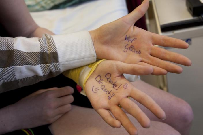 Zwei Hände liegen offen da, auf deren Handflächen motivierende Worte wie „Viel Glück“ und „Danke! Dir auch“ geschrieben sind.