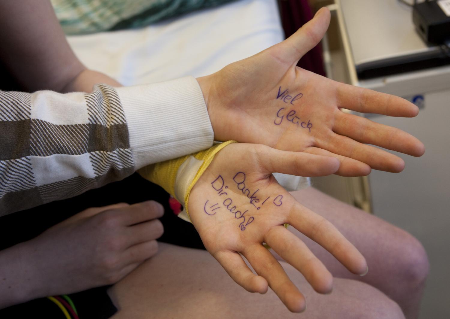 Zwei Hände liegen offen da, auf deren Handflächen motivierende Worte wie „Viel Glück“ und „Danke! Dir auch“ geschrieben sind.