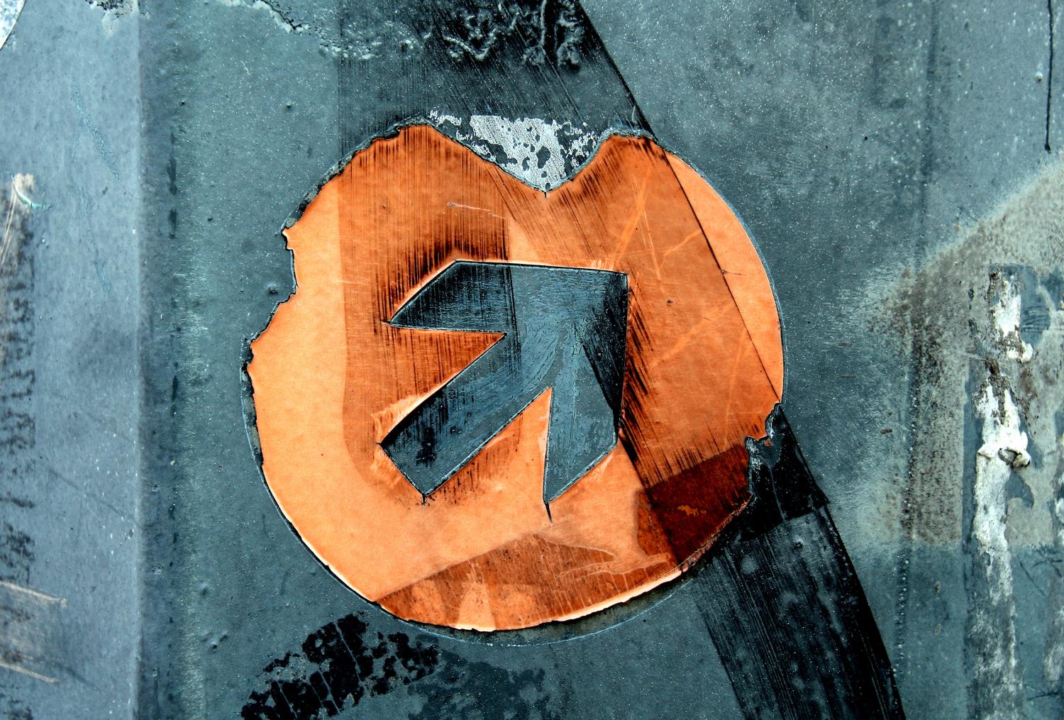 Ein blauer Pfeil, eingefasst von einem orangefarbenen Kreis.