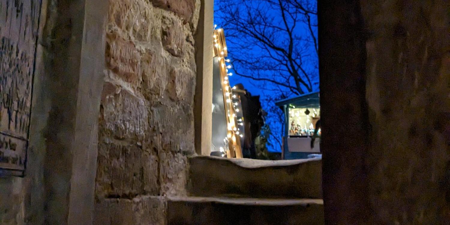 Blick durch einen alten Steinbogen auf eine Treppe, draußen leuchtet ein heller Stern am tiefblauen Abendhimmel.