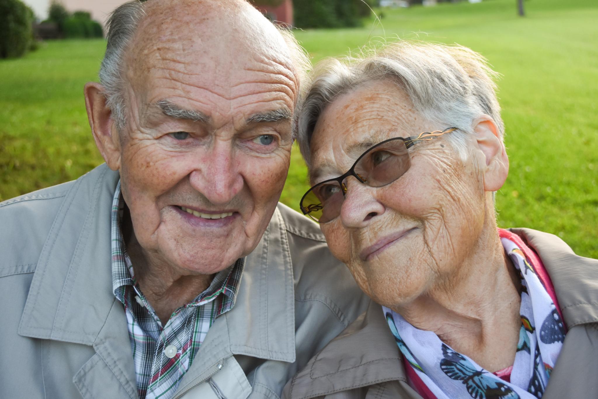 Voller Vertrautheit lehnt eine ältere Frau sanft ihren Kopf an den eines älteren Mannes.
