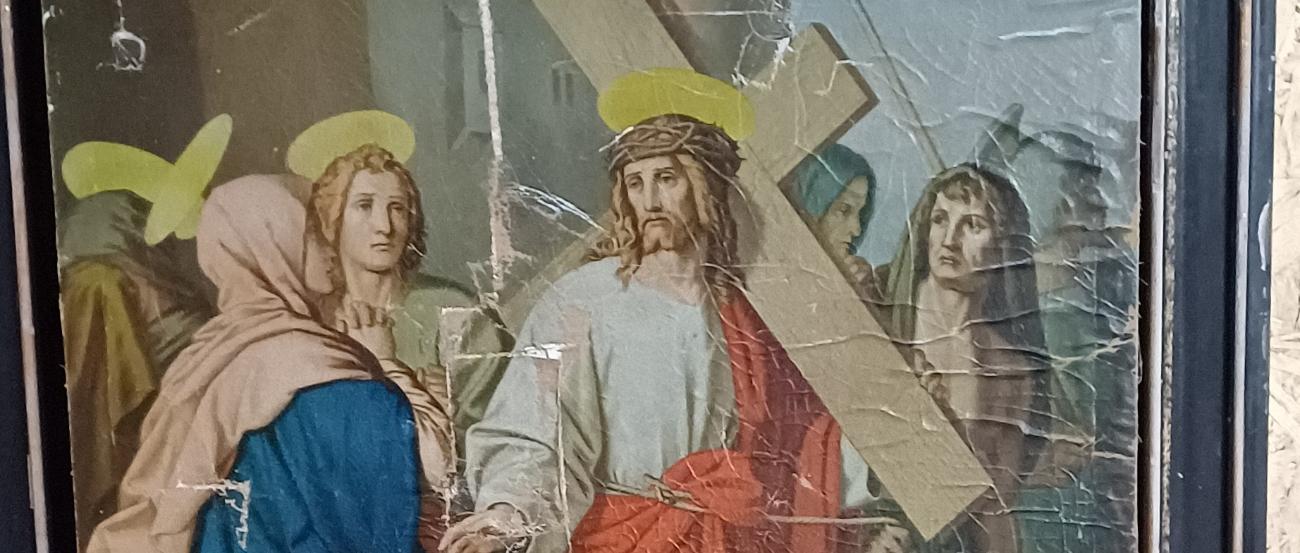 Jesus trägt ein großes Holzkreuz, umgeben von mehreren Personen. Er hat eine Dornenkrone und einen Heiligenschein, sein Gewand ist weiß mit einem roten Umhang, und das Bild zeigt deutliche Alters- und Gebrauchsspuren.