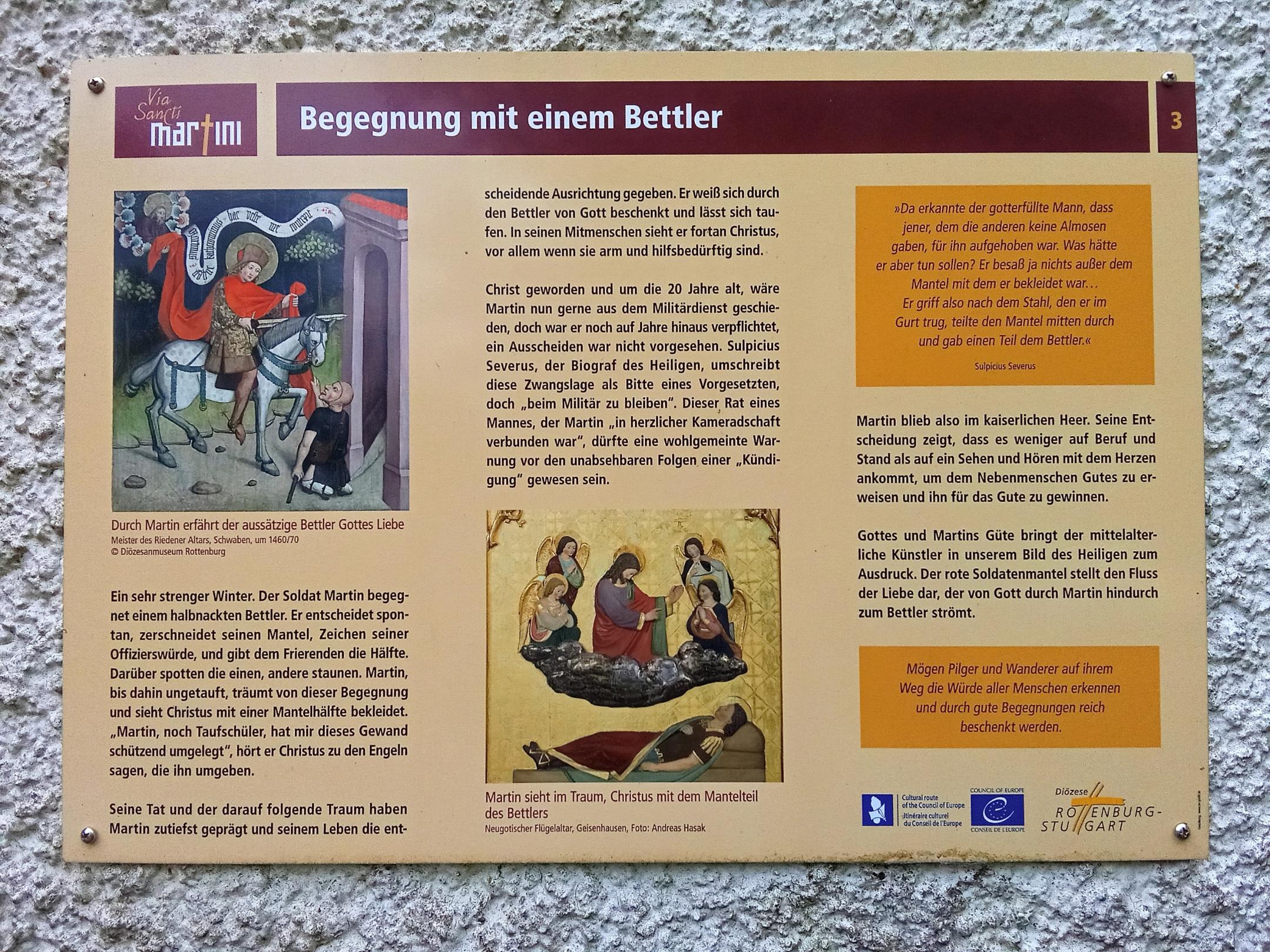 Ein Hinweisschild zeigt die Geschichte des heiligen Martin: In Bildern und Text wird dargestellt, wie ein Reiter seinen Mantel mit einem armen Bettler teilt.