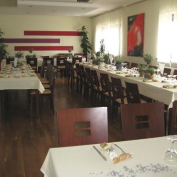 Ein festlich gedeckter Speiseraum mit langen, weiß eingedeckten Tischen und vielen Holzstühlen in einem hellen, warmen Ambiente. (c) Team Mehrgenerationenhaus Ein festlich gedeckter Speiseraum mit langen, weiß eingedeckten Tischen und vielen Holzstühlen in einem hellen, warmen Ambiente.