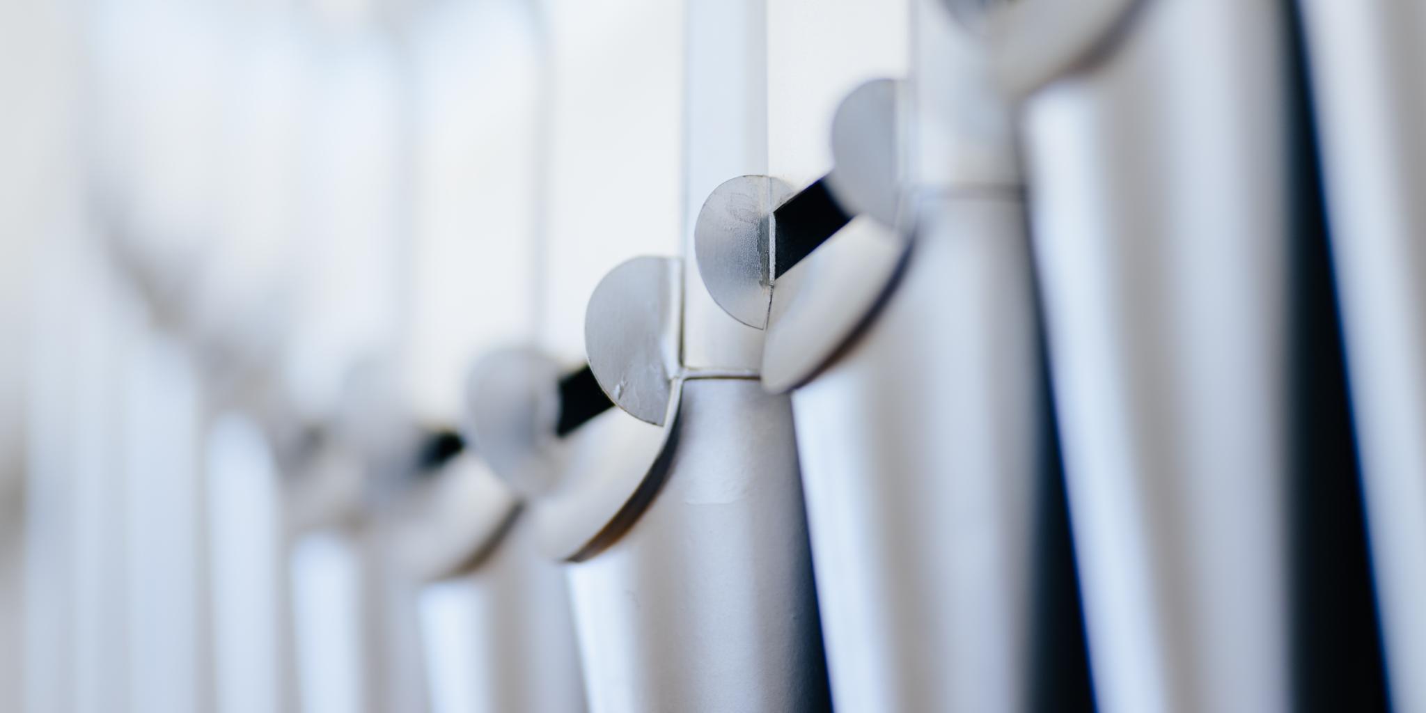 Das Foto zeigt eine Nahaufnahme von glänzenden Orgelpfeifen in einer Reihe.